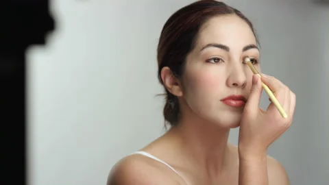 Close on beautiful brunette Hispanic model brushing eye shadow in slow motion Stock Footage 193903467