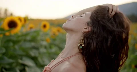 Close up of beautiful female model playing with hair in sunflower field Stock Footage 211450127