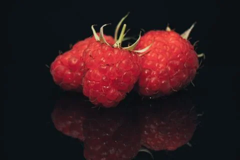 Close up Beautiful fresh raspberry on a black glass table dark background. Stock Photos