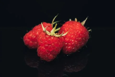 Close up Beautiful fresh raspberry on a black glass table dark background. Stock Photos
