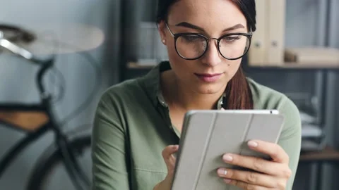 Close up of beautiful girl with glasses using tablet in workplace. Young woman Stock Footage 140557185