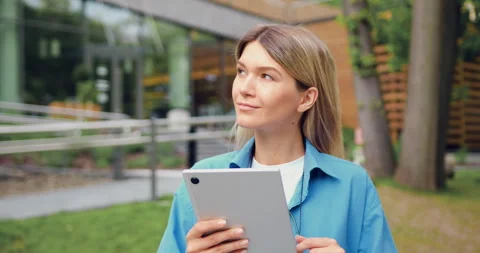 Close-up of beautiful girl smiling while using tablet in urban park during sunny Stock Footage 330335652