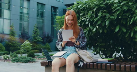 Close-up of beautiful girl smiling while using tablet in urban park during sunny Stock Footage 343769083