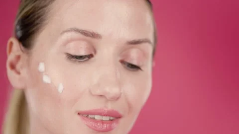 Close up of beautiful joyful and cheerful woman using anti wrinkle face cream Stock Footage