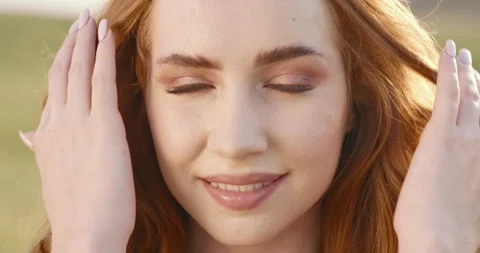 Close up of beautiful red-haired caucasian woman in field at sunset looking at Stock-Footage 243366563