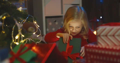 Close up of the beautiful small kid opening a box and looking at the x-mas Video stock 139434695