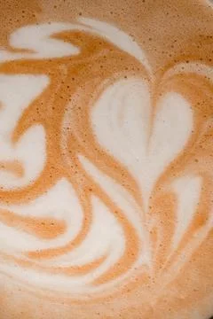 Close-up of beautiful white milk patterns on brown foam of coffee drink. Stock Photos