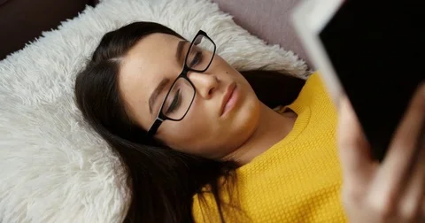 Close up beautiful woman lying on the sofa and studying, reading books at home Stock Footage