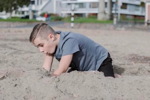 A close up of a beautiful young boy playing in the sand on the beach. Foto stock