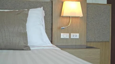 Close-up of bed with pillows and bedside lamp in hotel room Stock Photos