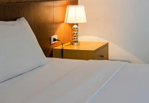 Close up of a bed with white sheets and lamp. Stock Photos