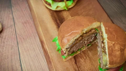 Close-up beef burger being sliced in half on the table in 4K. Stock Footage 153820771