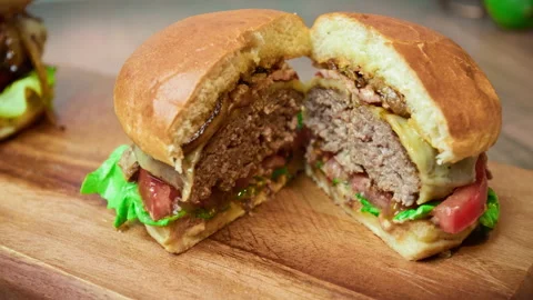 Close-up beef burger being sliced in half on the table in 4K. Stock Footage 153820955