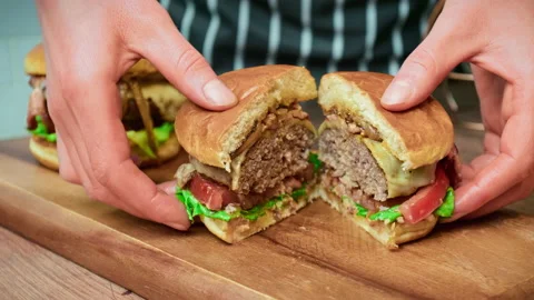Close-up beef burger being sliced in half on the table in 4K. Stock Footage 153821057