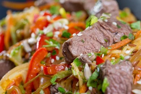 Close up of beef cuts, vegetables and spaghetti on a black plate Stock Photos