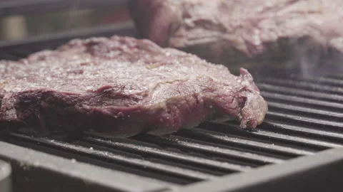 Close up on beef in the heat of the grill, ashes flying 库存影片 138540152