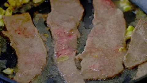 Close up of beef sizzling in frying pan with garlic and oil Stock Footage 331196401