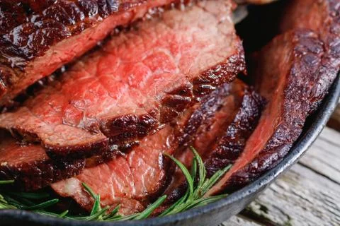Close up of a beef steak medium rare with baked garlic and rosemary in a blac Stock-Fotos