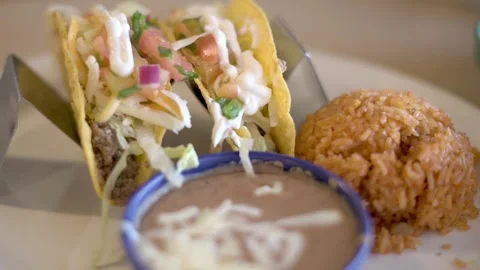Close-up of beef tacos served with refried beans and Mexican rice on a white  Stock Footage 276717836