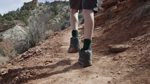 Close behind 8 year old boy hiking boots walking on dirt path desert mountain 스톡 동영상 248581201
