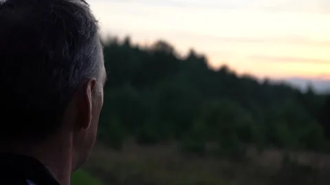 Close-up from behind of an elderly lonely man, looks thoughtfully at the sunset Stock Footage 139676811