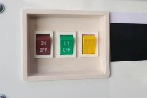 Close-up of a beige control panel with red, green, and yellow rocker switch.. Stock Photos