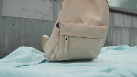 Close up of beige fabric backpack with visible stitching detail placed against Stock Footage 344874111