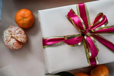 Close-Up of Beige Gift Box with Red Ribbon and Two Tangerines Stock Photos