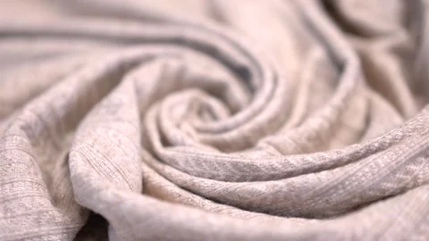 Close-up of a beige grey fabric rolled into a pattern slowly straightened Stock Footage 219755225
