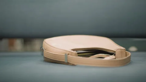 Close up beige handbag resting softly lit smooth blue surface open zipper 스톡 동영상 347980929