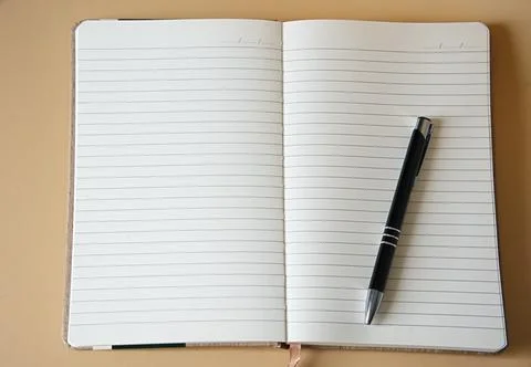 Close-up of a beige open lined notebook with a black pen Stock Photos