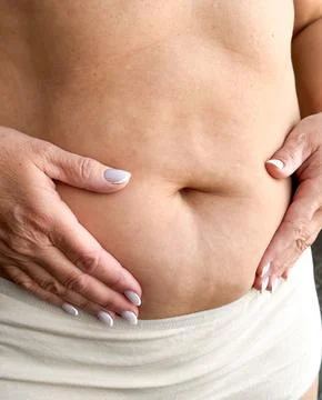 Close up of belly with hands gently touching in beige underwear on white Stock-Fotos