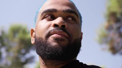 Close-up from below of black man blue hair looking around Stock Footage 287488376
