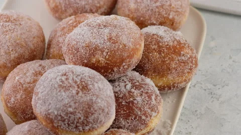 Close-up Berliners. Female hands lay donuts on a rectangular plate on a white Stock Footage 146867166