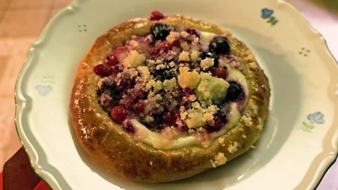 Close-up of a berry custard pastry on a pale ceramic plate, with golden glazed Video stock 340901232