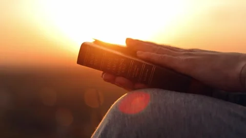 Close-up of a Bible in a woman's hands at sunset. Christianity Video stock 241811044