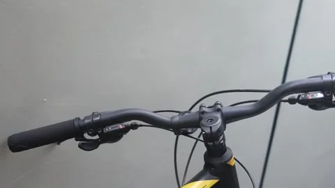 Close-up of a bicycle handlebar featuring a striking yellow and black grip, show Video stock 301582501