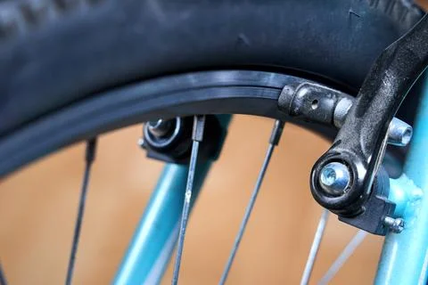 Close up of bicycle linear pull brake system pad touching metallic wheel rim  Stock Photos