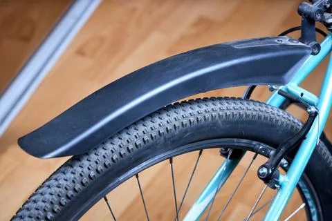 Close up of bicycle rear wheel featuring black plastic mudguard, knobby tire, Stock Photos