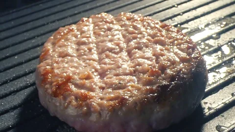Close-up big beef cutlet is grilled, the chef presses the cutlet with an iron Stock-Footage 115775197