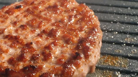 Close-up big beef cutlet is grilled, the chef presses the cutlet with an iron Stock Footage 115775421