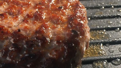 Close-up big beef cutlet is grilled, the chef presses the cutlet with an iron Stock Footage 115775500