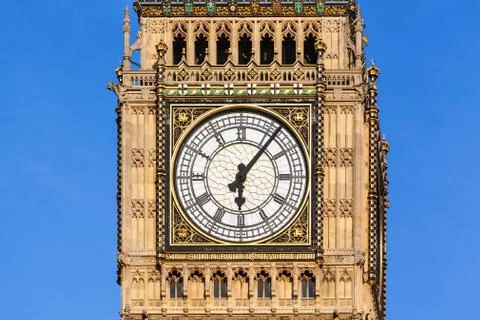 Close up of Big Ben's Clock Face with a clear blue sky behind Stock Photos