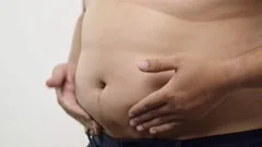 Obese man measuring waist with tape measure - SuperStock