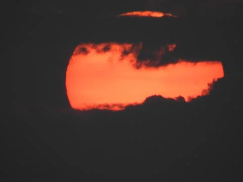 Close up of a big, yellow, setting sun in a red sky over the mountains of Ko Stock Photos