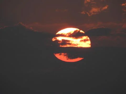 Close up of a big, yellow, setting sun in a red sky over the mountains of Ko Foto stock