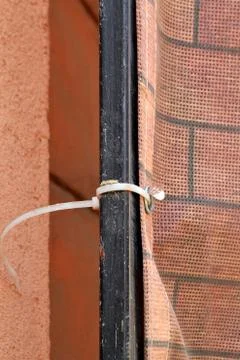 Close up of binding of construction mesh to scaffolding with cable tie Stock Photos