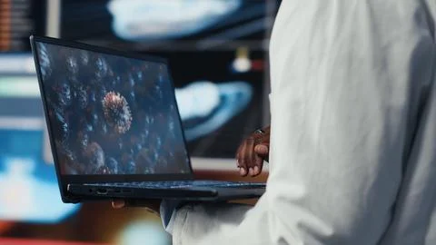 Close up of biomedical engineer studying pathogens using laptop Stockfoto's