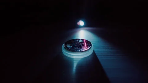 Close-up of a Bitcoin on a reflective surface with dramatic lighting Stock Footage 328285416