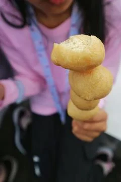 Close-up of a bitten deep-fried round snack on a skewer Stock Photos